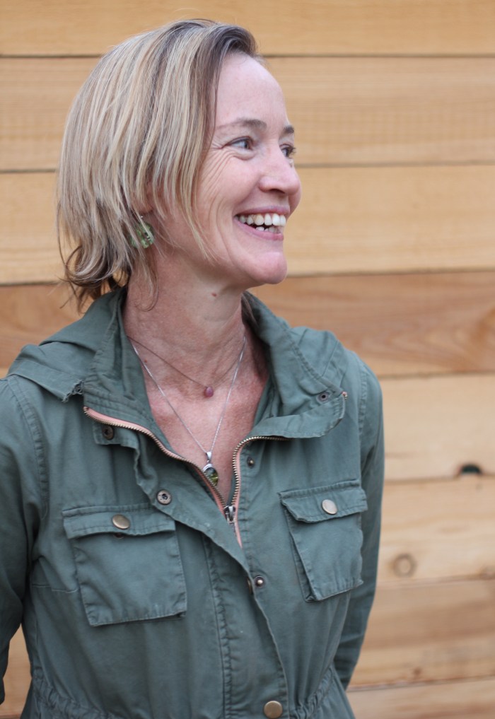 Maud looking away from the camera and smiling in front of a wood paneled wall